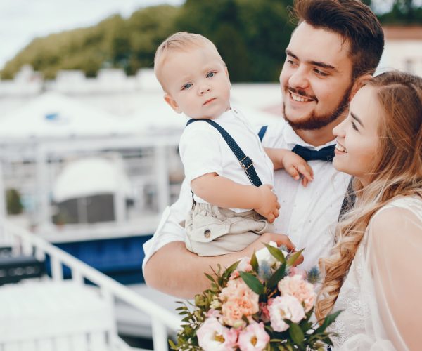 Elegant blonde in a white dress. Family standing in a park. Little cute boy with parents. Man in a white shirt